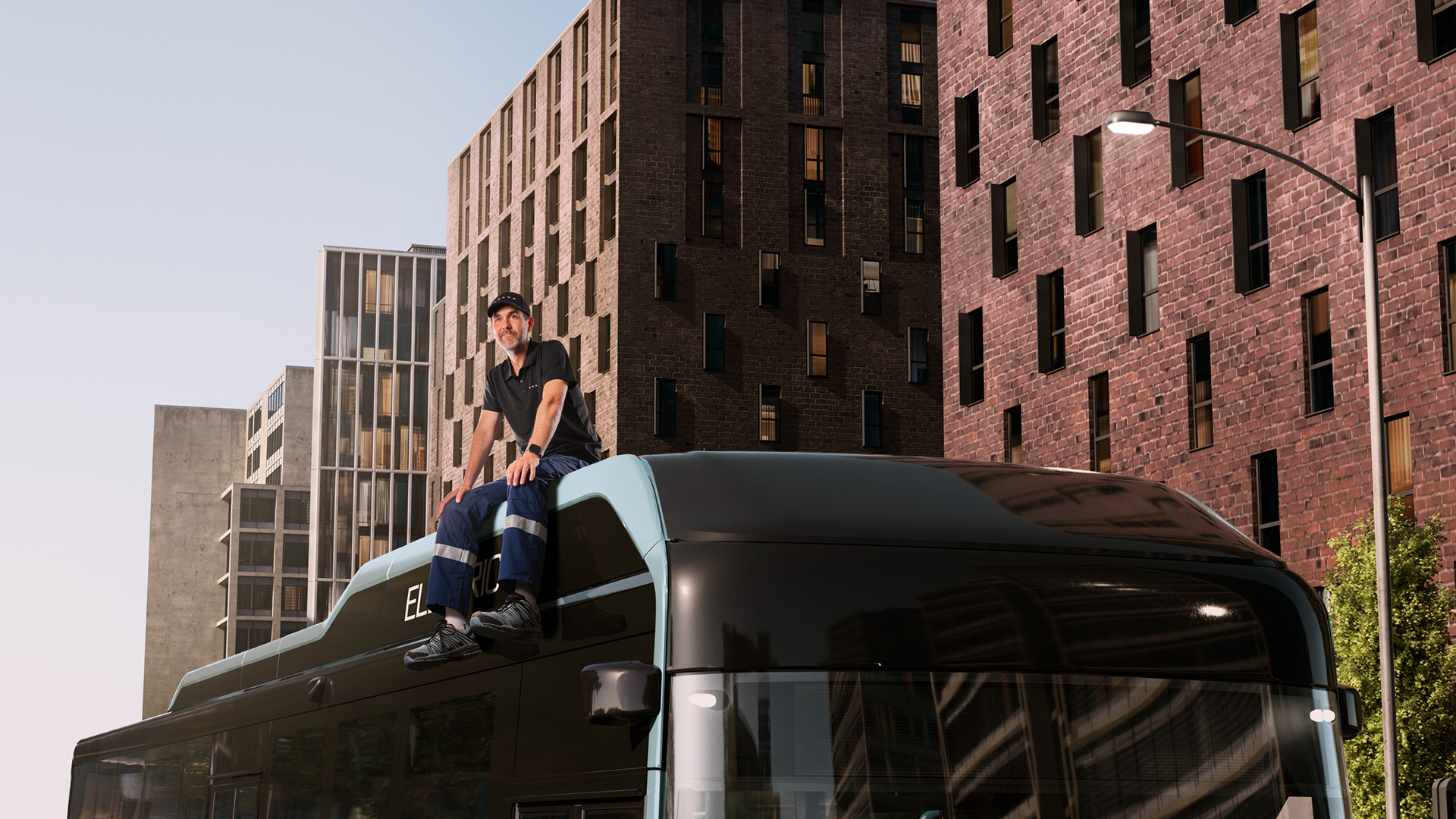 A Volvo service technician sitting on the roof of a Volvo 8900 Electric bus.